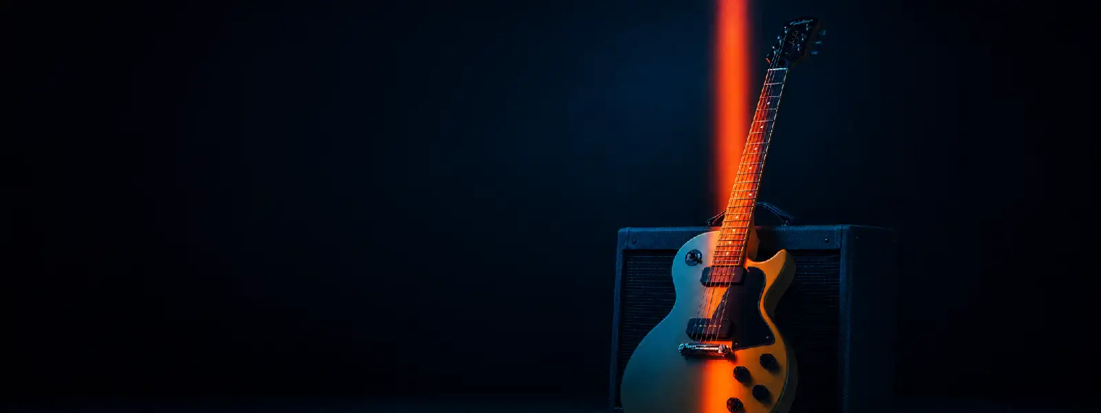 Chitarra elettrica appoggiata a un amplificatore sotto una luce di scena